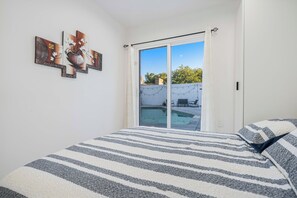 A bedroom with a bed, a sliding glass door leading to a balcony, and a wall with framed artwork. - Fully Equipped ADU Close to Business Centers, Hospital Centers, & Attractions (Los Angeles)