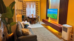 A modern living room with a sofa, TV, and air conditioning unit. - Ocean Blue cozy airbnb with pool/gym. Perfect for relaxing and staying active. (Kampala)