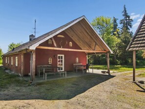 Ein rotes Gebäude mit einem Holzdach, einer Bank und einem Tisch vor der Fassade.