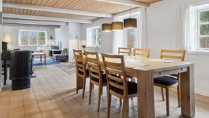 Un coin repas avec une table et des chaises en bois, un radiateur noir et de grandes fenêtres.