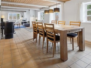 Ein Essbereich mit Holztisch und Stühlen, einem schwarzen Heizgerät und großen Fenstern.