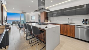 A modern kitchen with a central island, stainless steel appliances, and a view to the outside. - Oceanview 2BR Near Beach + Golden Zone Rooftop (Bucerías)