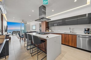 A modern kitchen with a central island, stainless steel appliances, and a view to the outside. - Oceanview 2BR Near Beach + Golden Zone Rooftop (Bucerías)