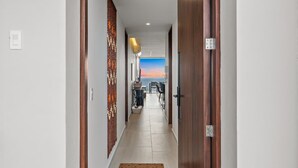A hotel corridor with wooden doors, a reception desk, and a view of the sea. - Oceanview 2BR Near Beach + Golden Zone Rooftop (Bucerías)