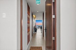 A hotel corridor with wooden doors, a reception desk, and a view of the sea. - Oceanview 2BR Near Beach + Golden Zone Rooftop (Bucerías)