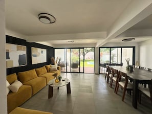 Ein modernes Wohnzimmer mit Sofa, Couchtisch und Essbereich.