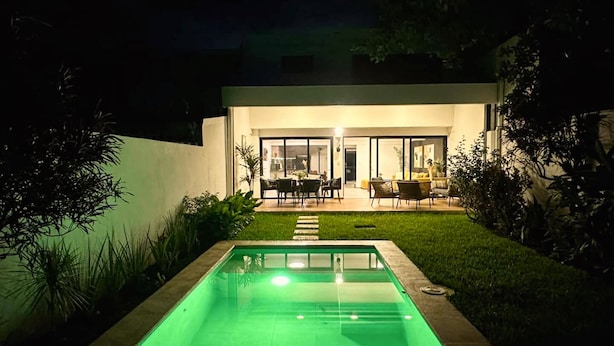 Una casa moderna con piscina, patio arredato e interni luminosi.