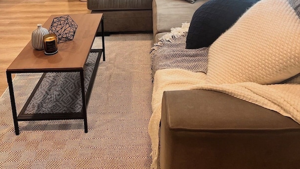 A modern living room with a sofa, coffee table, and a mirror. There are shelves with decorative items and a plant. - Napa Home 10 Minutes from BottleRock & Downtown (Napa)
