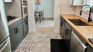 A narrow kitchen with a microwave, oven, and dishwasher. There is a dining area with a table and chairs visible through an open doorway. - Napa Home 10 Minutes from BottleRock & Downtown (Napa)