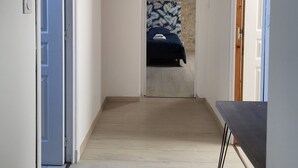 A hallway with a ceiling fan, a bed with a patterned bedspread, and a wooden door on the right. - Charming gîte near Gourdon - stone, nature, enclosed garden, terrace (Concorès)