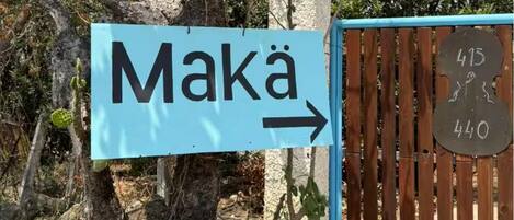 A directional sign for Maká with an arrow pointing to the right, and a gate with numbers 415 and 440 on it.