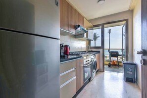 Une cuisine moderne dotée d’appareils électroménagers en acier inoxydable, de meubles en bois et offrant une vue sur la plage grâce à de grandes fenêtres.