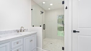 A bathroom with a shower, a sink, and a mirror.