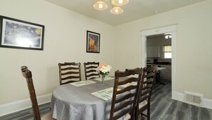 A dining area with a table set for four, wooden chairs, a chandelier, and two framed artworks on the wall. - Welcome to the Blue Oasis! Come stay with us in our fully furnished 4-bedroom (Roanoke)