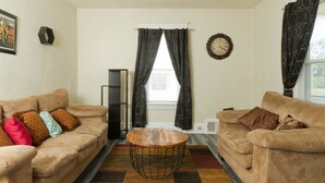 A living room with two sofas, a coffee table, a ceiling fan, a clock, and a window with curtains. - Welcome to the Blue Oasis! Come stay with us in our fully furnished 4-bedroom (Roanoke)