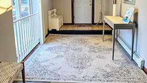 A room with a patterned carpet, a bench, a door, a coat rack, and a mirror on the wall. - The off Main beach retreat! a spacious and cozy 6 bedroom home. (South Kingstown)