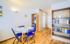 Ein Zimmer mit Esstisch, Stühlen, einem Bücherregal und einer Schiebetür.