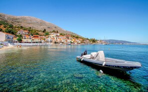 A coastal town with clear waters, a boat docked, and buildings along the shore. - Oeve Apartment - A Colourful Loft in Kefalonia (Kefalonia)