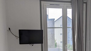 Una habitación con ventana, radiador, escritorio y televisión.