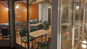 Un restaurante con paredes de vidrio, sillas verdes y mesas.