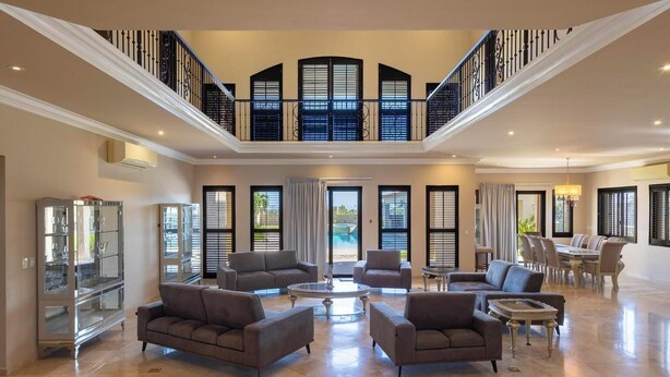 Un salon spacieux avec un plafond haut, un balcon et un coin repas.