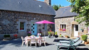 A stone building with a patio area, outdoor seating, and potted plants. - Ker Monette - PORDIC (PORDIC)
