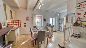 A kitchen with a dining area, a refrigerator, a sink, and a window with curtains. - Ker Monette - PORDIC (PORDIC)