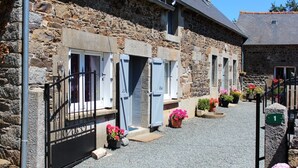 A stone building with multiple windows and doors, a gravel driveway, and potted plants. - Ker Monette - PORDIC (PORDIC)