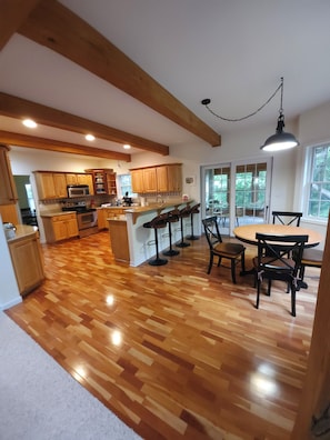 Une cuisine spacieuse avec des meubles en bois, un coin repas comprenant une table et des chaises, et une grande fenêtre offrant une vue sur l’extérieur.
