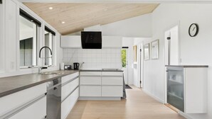 A modern kitchen with white cabinetry, a wooden ceiling, and a built-in microwave.