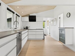 Eine moderne Küche mit weißen Schränken, einer Holzbalkendecke und einer eingebauten Mikrowelle.