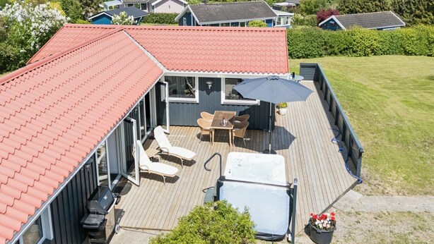 A residential property with a deck, outdoor seating, and a hot tub.
