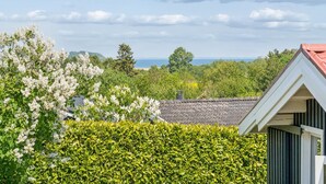 A residential area with a house, lush greenery, and a view of the sea.