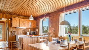 En stuga byggd av trä med kök, matplats och stora fönster.