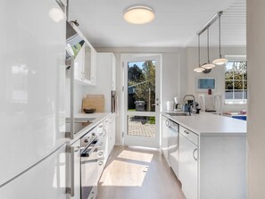 Una cocina moderna con armarios blancos, horno empotrado y una isla grande con pileta.