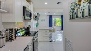 Une cuisine moderne avec des armoires blanches, une cuisinière en acier inoxydable et un tabouret de bar.