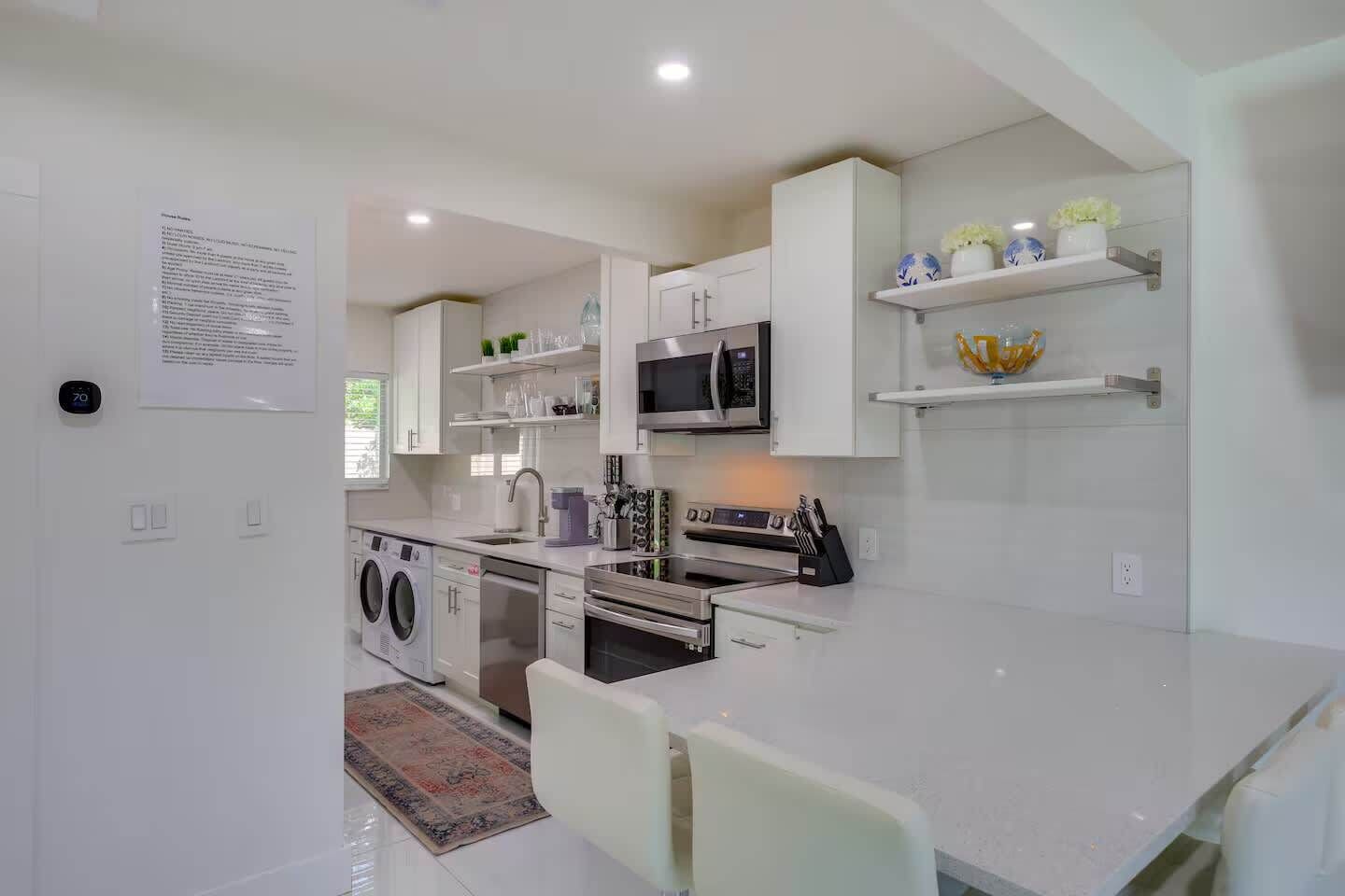 A modern kitchen with built-in appliances, a dining area, and a laundry machine.