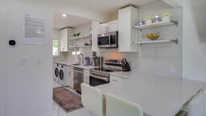Une cuisine moderne dotée d’appareils électroménagers intégrés, d’un coin repas et d’un lave-linge.