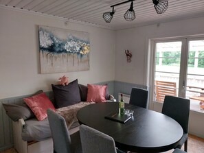 A room with a round table, a sofa with cushions, a painting on the wall, and a window with a view. - Family House Near Tiveden National Park with fireplace, piano, big property (Finnerödj)
