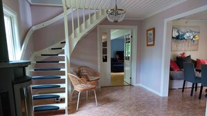A living room with a staircase, a fireplace, a dining area, and a painting on the wall. - Family House Near Tiveden National Park with fireplace, piano, big property (Finnerödj)