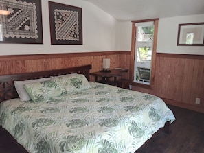 A room with a bed, a small table, a chair, and a window. - Two houses for the price of one at beautiful orchid farm. (Pāhoa)