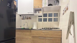 Une cuisine avec un réfrigérateur noir, des armoires en bois, un évier et une cuisinière.