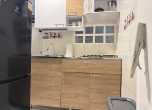 Eine Küche mit einem schwarzen Kühlschrank, Holzschränken, einer Spüle und einem Herd.