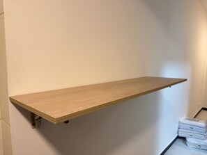 Ein an der Wand in einer Ecke montiertes Holzregal, mit einer Ansammlung weißer Gegenstände auf dem Boden in der Nähe.