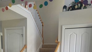 Un escalier avec des rampes en bois et des marches recouvertes d’une moquette beige, menant à une porte blanche.