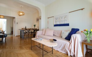 Ein gemütliches Wohnzimmer mit Holzboden, einer Couch, einem Couchtisch und einem Essbereich mit Stühlen und einem Tisch.