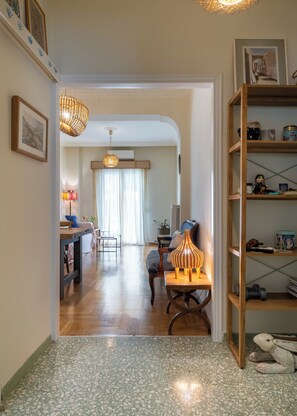 Ein Wohnzimmer mit Holzboden, einem Essbereich mit Tisch und Stühlen, einem Bücherregal und einer Pendelleuchte.