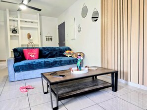 Ein Wohnzimmer mit einem blauen Sofa, einem Couchtisch und einem Deckenventilator.