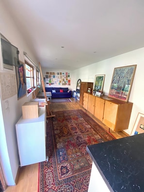 A compact living space with a kitchen area, a dining table, a sofa, and a patterned rug.