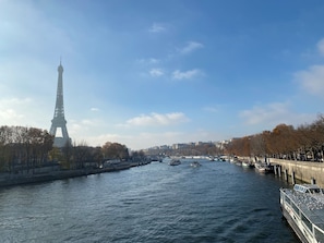 A river with boats, a bridge, and the Eiffel Tower in the background.